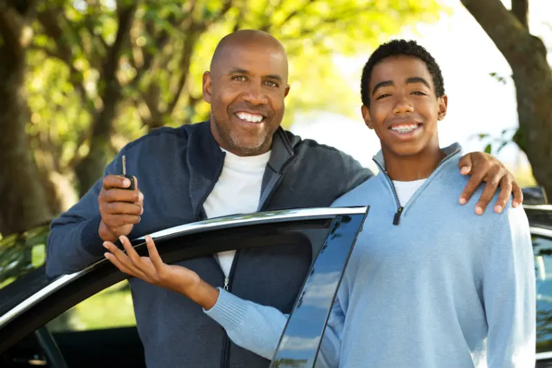 A man and boy holding a skateboard in the park.