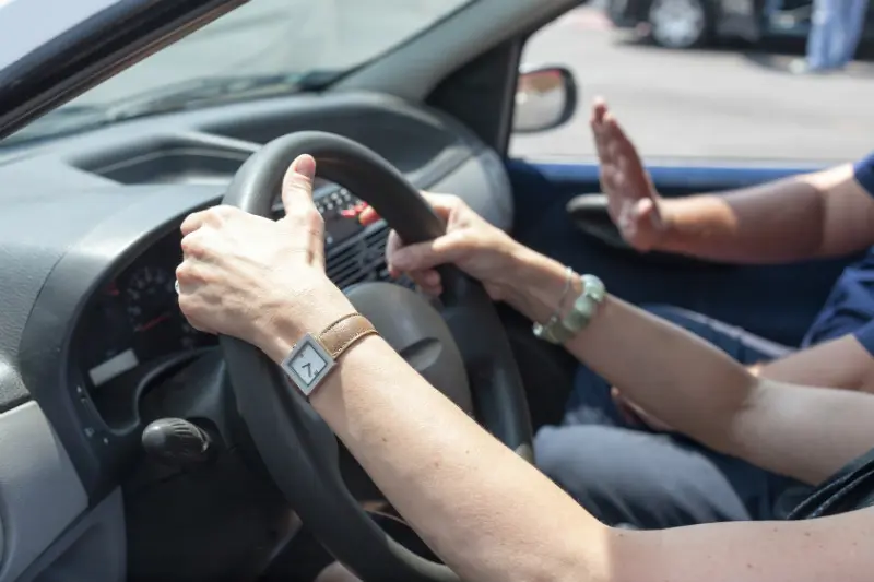 A person driving in the car with their hand on the steering wheel.